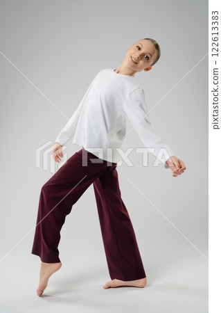 Girl gracefully dancing in maroon pants and white top during a performance 122613383