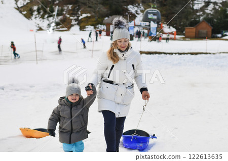 A mother with son sledding in the snow A mother with son sledding in the snow 122613635