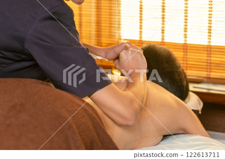 A female masseur massages a woman's back and neck. 122613711