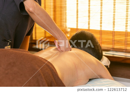 A female masseur massages a woman's back and neck. A female masseur massages a woman's back and neck. 122613712