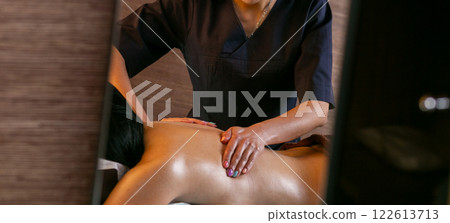 A female masseur massages a woman's back and neck. A female masseur massages a woman's back and neck. 122613713