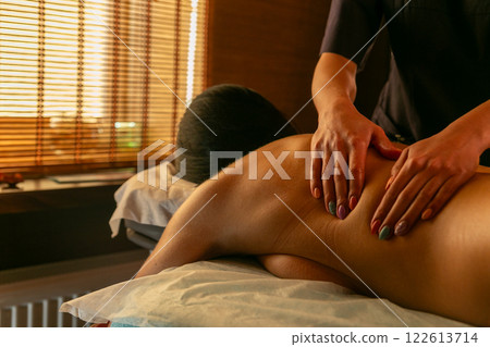 A female masseur massages a woman's back and neck. 122613714