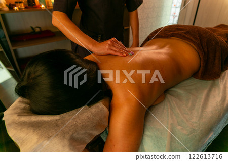 A female masseur massages a woman's back and neck. A female masseur massages a woman's back and neck. 122613716