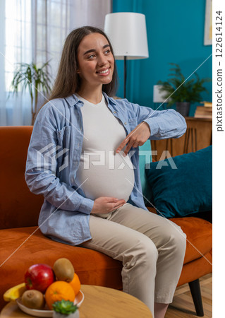 Happy pregnant woman walks her fingers over her large belly expecting baby playing with unborn child 122614124