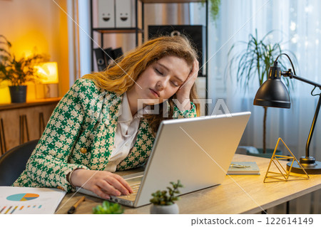 Bored sleepy businesswoman worker working on laptop computer leaning on hand at office desk 122614149