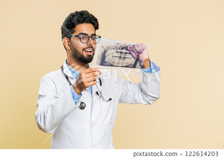 Indian young doctor orthodontist man examines a panoramic x-ray picture of the jaw teeth stomatology Indian young doctor orthodontist man examines a panoramic x-ray picture of the jaw teeth stomatology 122614203