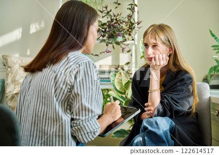 Sad upset young teenage female patient talking to professional mental therapist Sad upset young teenage female patient talking to professional mental therapist 122614517