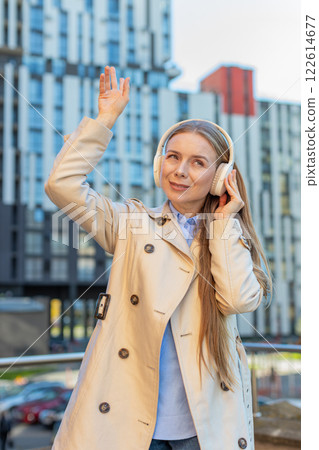 Happy mature businesswoman in wireless headphones dancing listening to music on downtown street 122614677