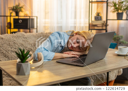Tired young woman working on laptop exhausted at home, fatigue, falling asleep lying on keyboard Tired young woman working on laptop exhausted at home, fatigue, falling asleep lying on keyboard 122614729