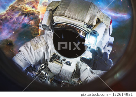 Astronaut in a spacesuit floating in space stardust and carina nebula on the background. View from an illuminator of orbital station. 122614981