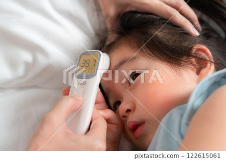 Parent measuring temperature of sick child with digital thermometer for health checkup at home Parent measuring temperature of sick child with digital thermometer for health checkup at home 122615061