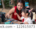 Asian Mother and Asian Daughter Painting Together in an Outdoor Art Workshop with Creative Atmosphere 122615073
