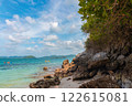 Serene Beach Landscape with Clear Water, Rocks, and Kayakers Under Bright Blue Sky 122615081