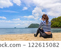 Serene Beach Scene with Woman Sitting on Shoreline and Enjoying Beautiful Ocean Views 122615082