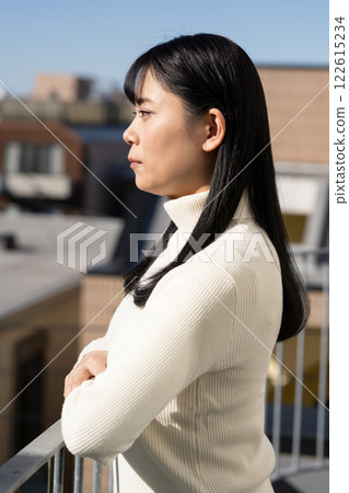 Young woman standing on the balcony of an apartment 122615234