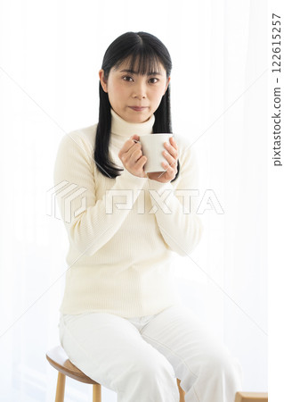 Woman drinking a hot drink from a mug 122615257