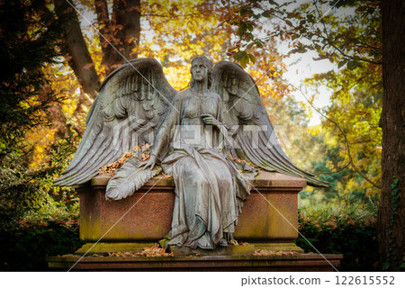 a statue of an angel with spread wings sits on a gravestone in the picturesque autumnal Melaten cemetery in cologne 122615552