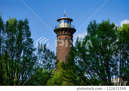 the historic helios lighthouse behind trees and against a blue sk the historic helios lighthouse behind trees and against a blue sk 122615589
