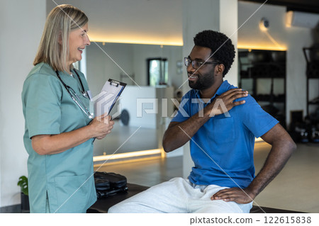 Female physical therapist talking to male patient and making notes 122615838