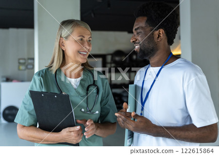 Female doctor in medical scrubs with an african american intern in the clinic 122615864