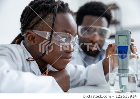 Teacher and student working in a school laboratory and looking involved and focused Teacher and student working in a school laboratory and looking involved and focused 122615914