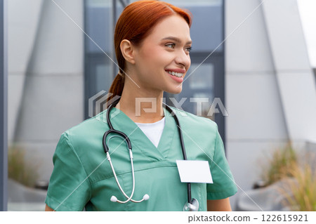Redhead woman physician wearing uniform standing indoor in medical clinic Redhead woman physician wearing uniform standing indoor in medical clinic 122615921