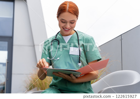 Redhead woman doctor practitioner wearing uniform standing in medical office 122615927