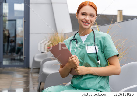 Redhead woman physician wearing uniform standing indoor in medical clinic Redhead woman physician wearing uniform standing indoor in medical clinic 122615929