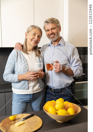 Mature retired couple relaxing at kitchen table drinking tea enjoying morning routine Mature retired couple relaxing at kitchen table drinking tea enjoying morning routine 122615946
