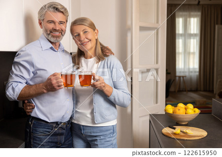 Happy elderly man and woman smiling while sharing healthy breakfast with tea at home 122615950
