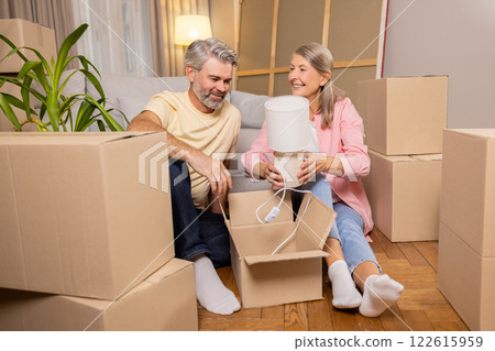 Senior couple moving to new home family unpacking boxes of things 122615959