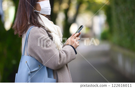 一名中年婦女穿著外套和口罩在鎮上行走 122616011