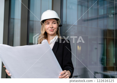 Young female engineer in a hard cap with a project scheme in hands 122616125