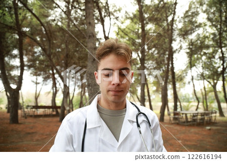 Doctor Reads Patients Diagnosis In Park With Trees Outside Hospital 122616194