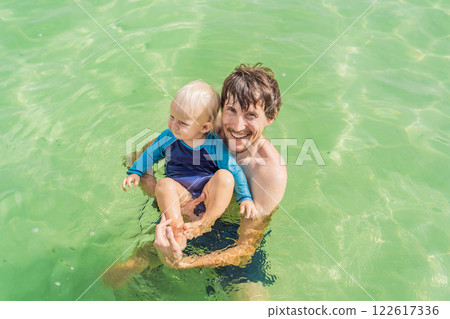 Father with his toddler son swimming in the turquoise waters of Lake Bacalar. Family bonding, summer vacation, and outdoor fun in Quintana Roo, Mexico concept Father with his toddler son swimming in the turquoise waters of Lake Bacalar. Family bonding, summer vacation, and outdoor fun in Quintana Roo, Mexico concept 122617336