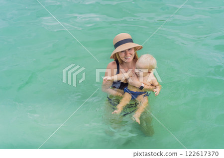 Mother with her son swimming in the turquoise waters of Lake Bacalar. Family bonding, summer vacation, and outdoor fun in Quintana Roo, Mexico concept Mother with her son swimming in the turquoise waters of Lake Bacalar. Family bonding, summer vacation, and outdoor fun in Quintana Roo, Mexico concept 122617370