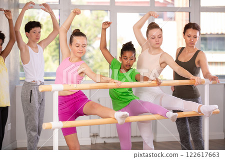 Group of teenage dancers practicing stretching at barre Group of teenage dancers practicing stretching at barre 122617663
