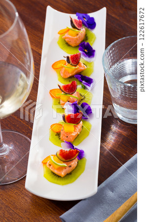 Ceviche from pickled red fish and cumquat a circle of kiwi, with figs at plate Ceviche from pickled red fish and cumquat a circle of kiwi, with figs at plate 122617672