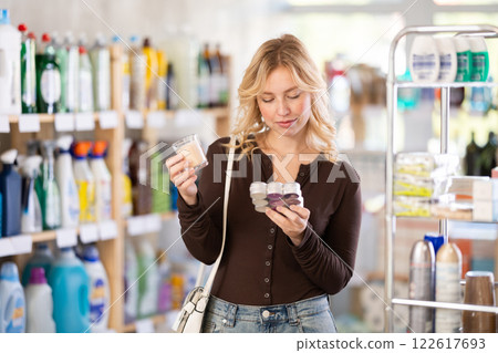 Girl housewife in household store examines goods, chooses candle 122617693