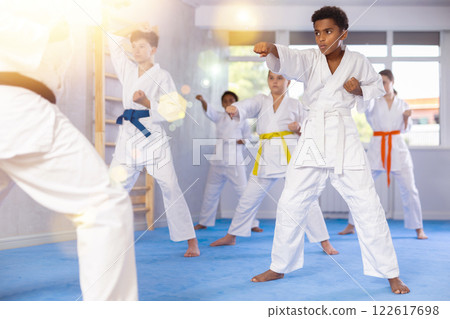 Black teenager practicing punches during group martial arts workout 122617698