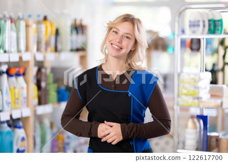 Young woman seller stands in trading hall of household store, invite for purchase Young woman seller stands in trading hall of household store, invite for purchase 122617700