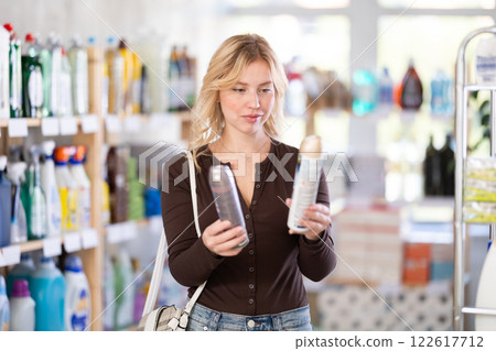 Girl housewife in household store examines goods, chooses room spray aerosol 122617712