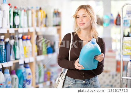 Young girl looking for household detergents on shelves in store 122617713