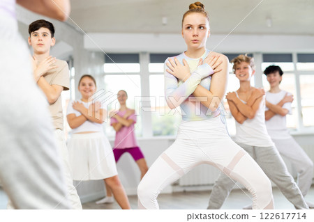 Group of teenagers learn to dance hip-hop and other modern dances in spacious dance studio 122617714