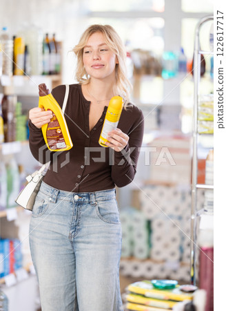 Girl housewife in household store examines goods, chooses liquid furniture polish 122617717