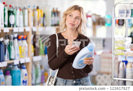 Before making purchase, girl buyer scan QR code on packaging of liquid detergent 122617827