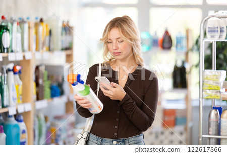 Before making purchase, girl buyer scan QR code on packaging of glass cleaner spray Before making purchase, girl buyer scan QR code on packaging of glass cleaner spray 122617866