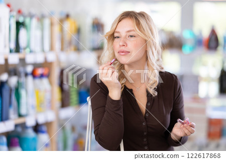 Girl housewife in cosmetic store examines goods, chooses facial powder 122617868
