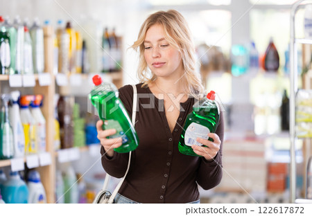 Focused young Woman choosing dishwashing liquid on supermarket shelf 122617872