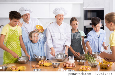 Two friendly chefs giving culinary lesson to group of tweens 122617873